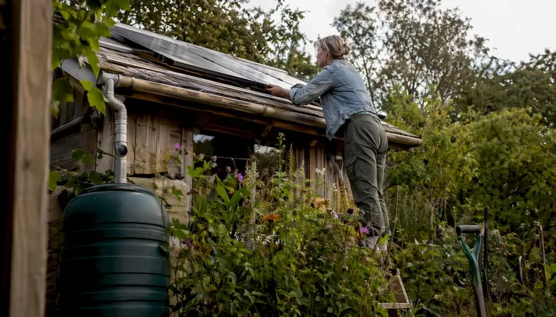 Man adjusting solar panels at off-grid UK cottage